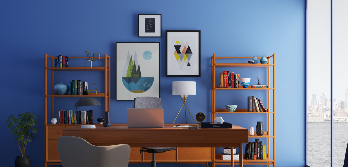Blue painted office with two chairs, desk, bookshelves, and a photo gallery on the wall.